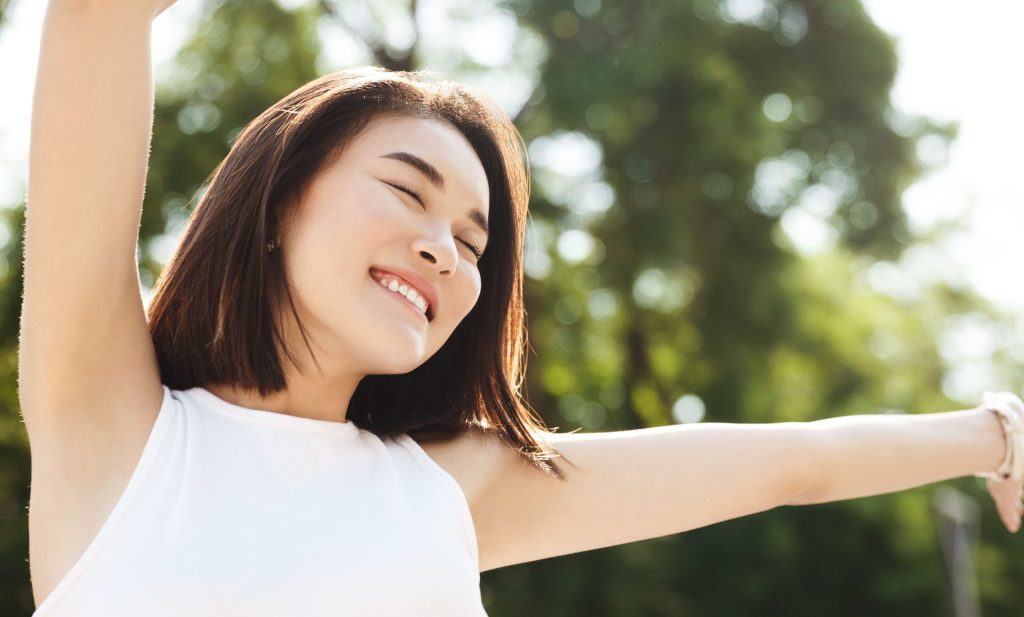 叮咚News｜分享新奇與樂趣 - close up asian woman stretching hands up smiling walking park looking carefree happy 1